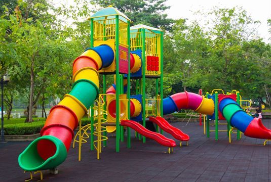 A colorful playground set in a park with trees in the background.