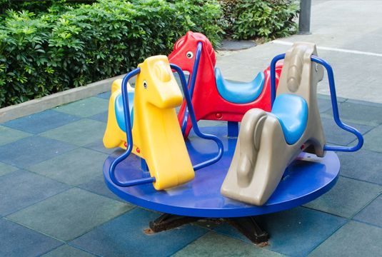 A merry go round with horses on it in a playground.