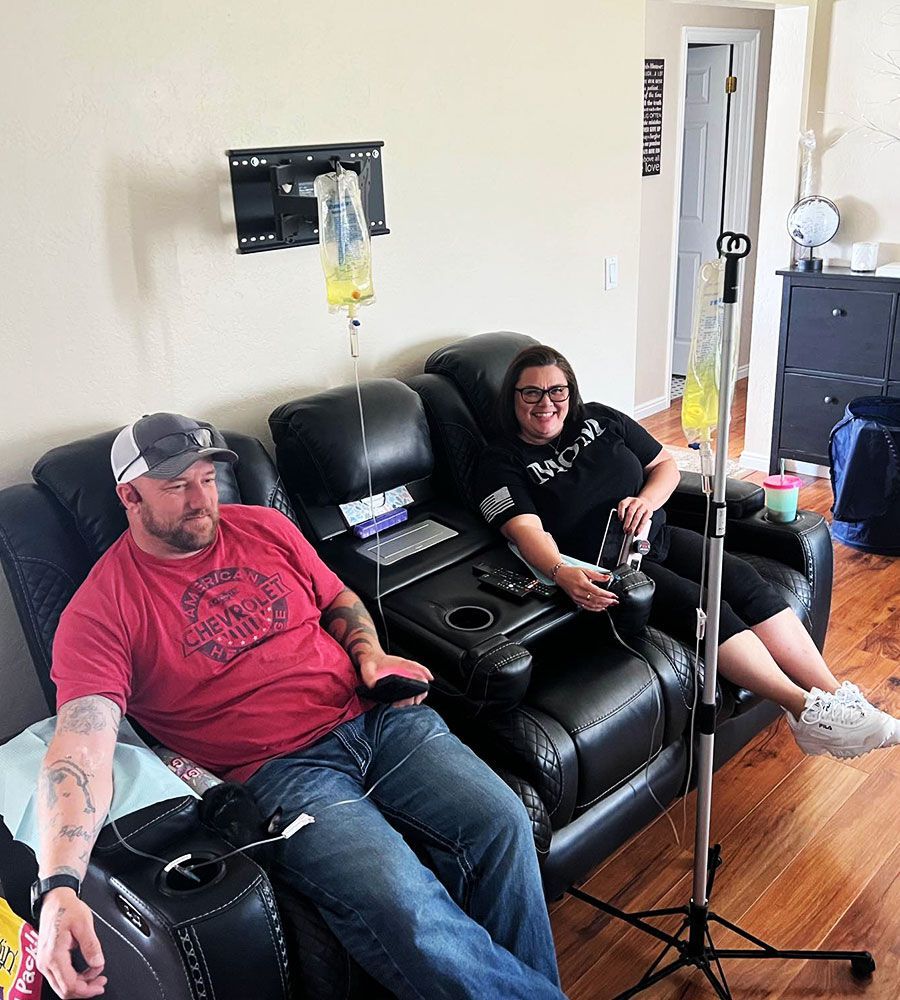 A couple enjoying at-home IV infusion therapy in their living room recliners.