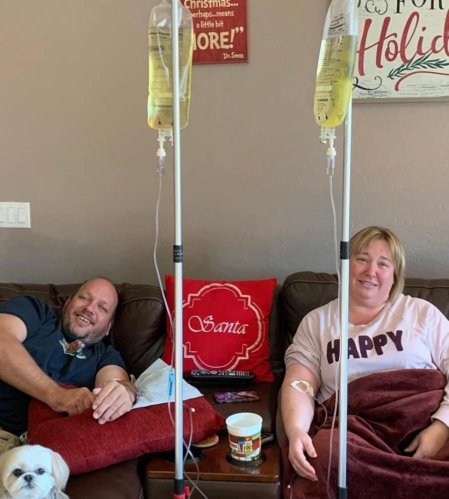 Comfortable at-home IV therapy service for two people, showing convenience and relaxation on a brown sofa.