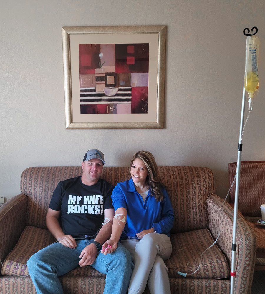 A husband and wife sitting together on a couch during a mobile IV wellness and recovery session.