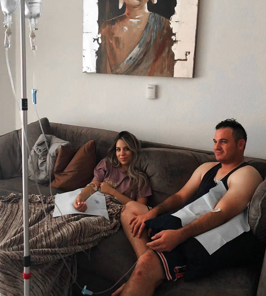 Convenient at-home IV therapy service for two people, promoting relaxation and recovery on a comfortable sofa.