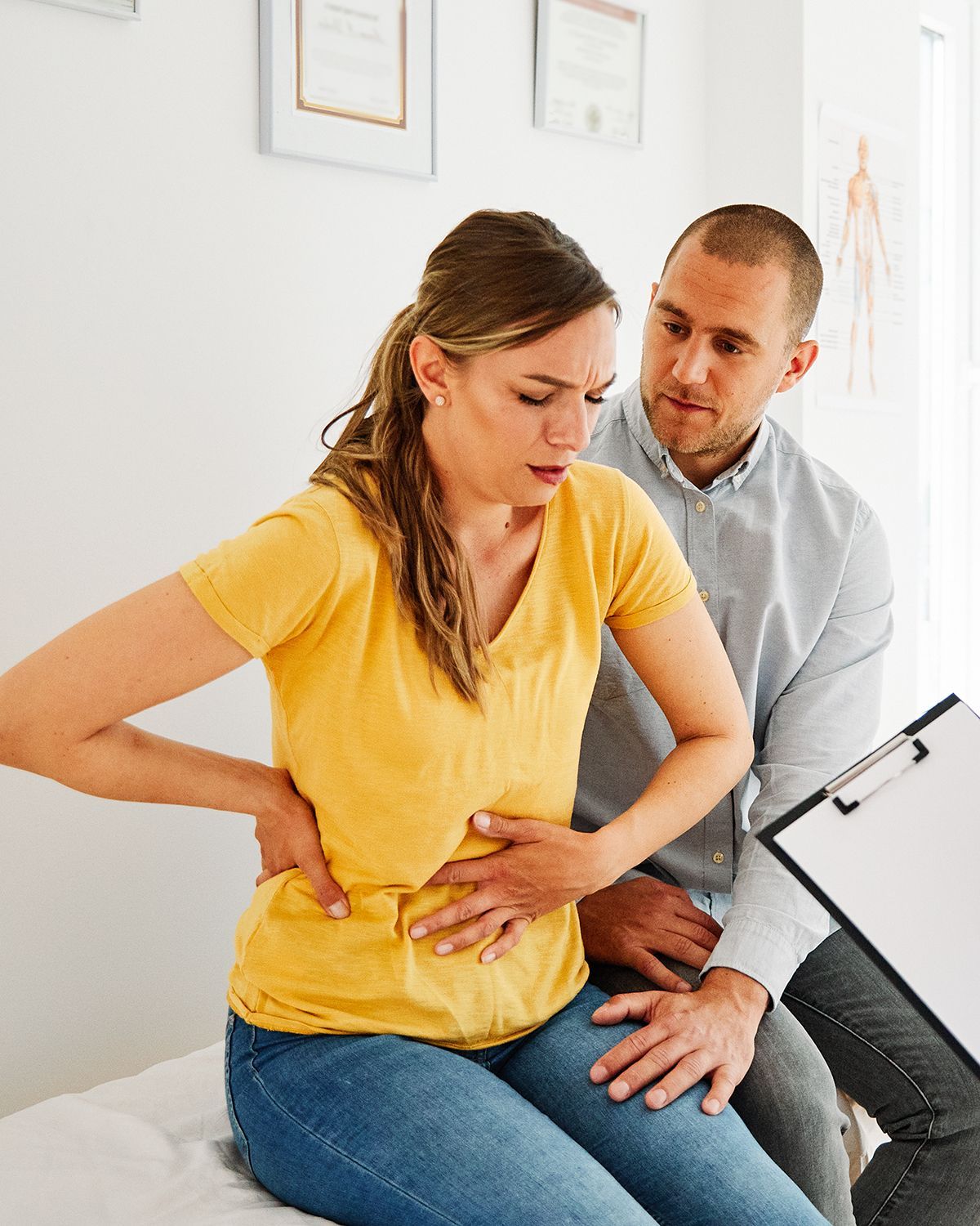 A medical professional in scrubs prepares an IV for a patient in a white robe seated in a chair.