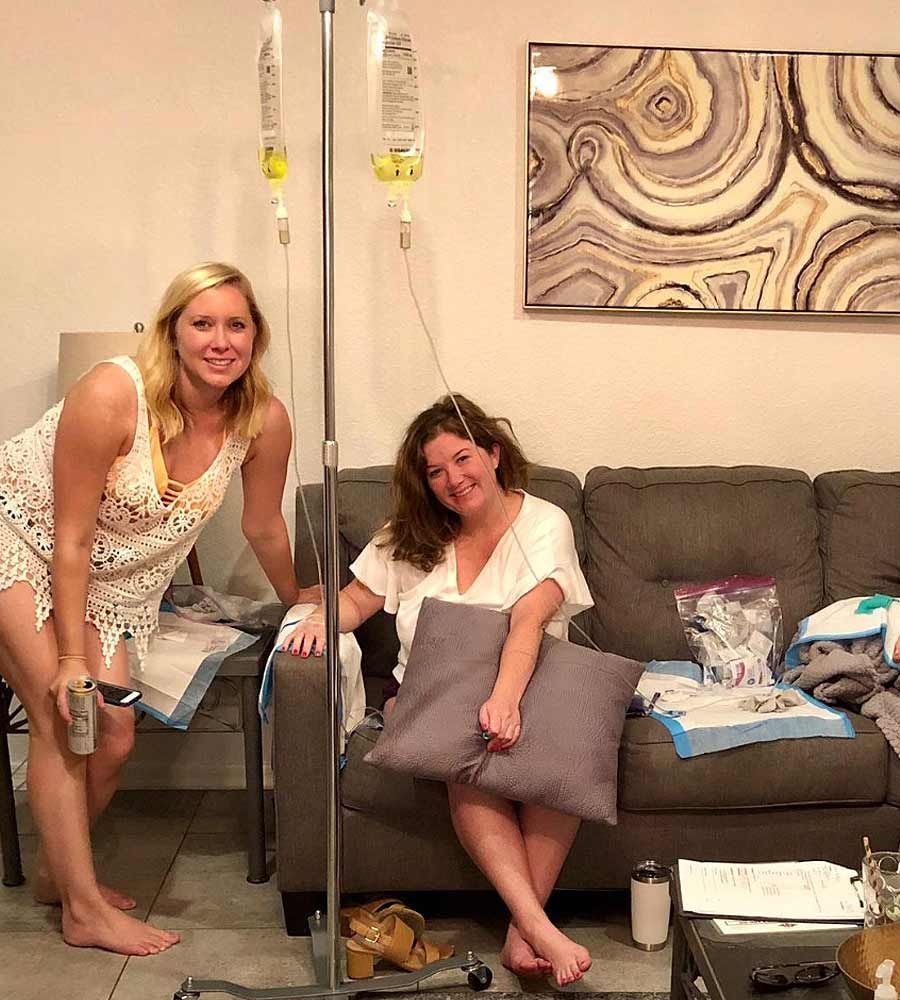 Women relaxing on a couch, one receiving a mobile IV therapy infusion.