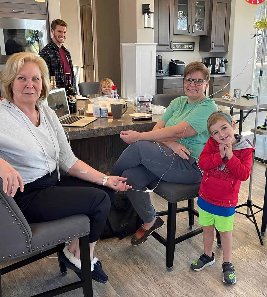 Happy young man receiving a comfortable, in-home IV vitamin therapy infusion on his living room couch.