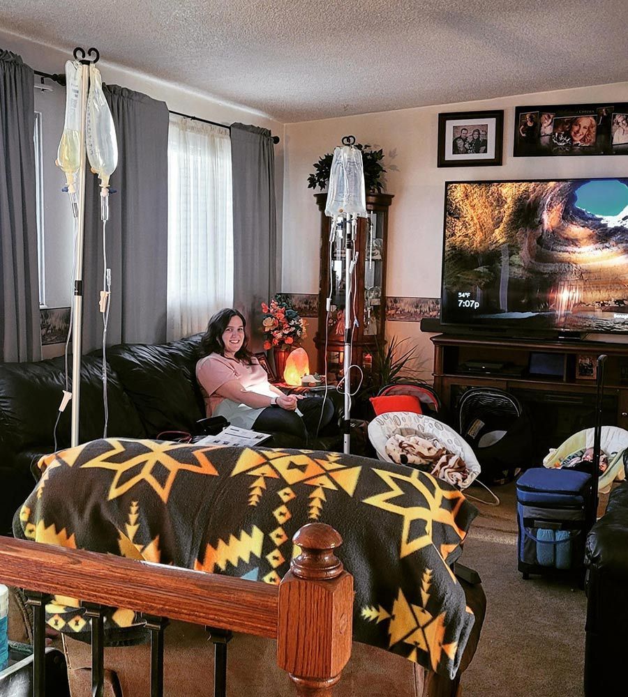 A woman smiling while receiving a mobile IV hydration treatment in her cozy living room.