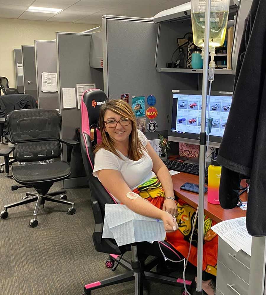 An office worker receiving an IV infusion while staying productive at their desk.