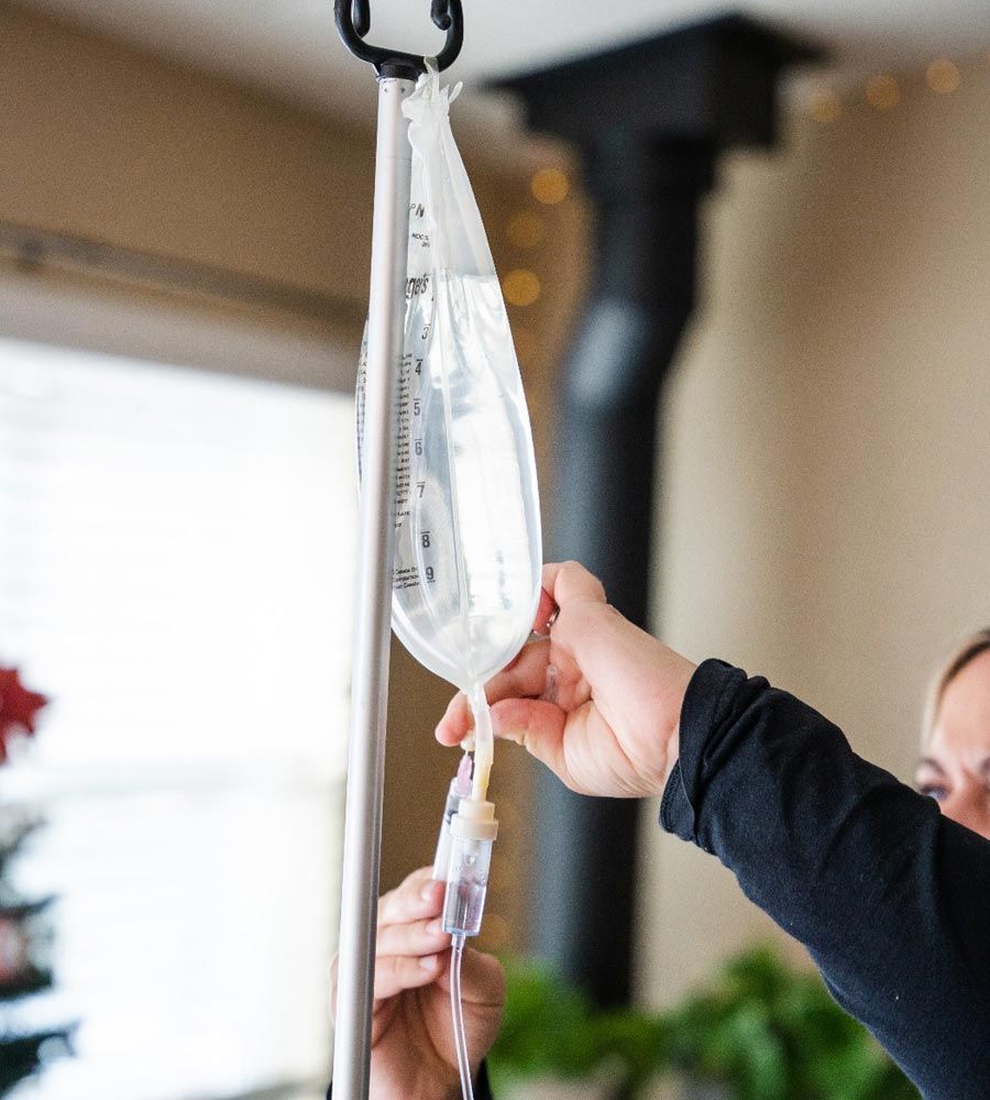 Close-up of a nurse adjusting the IV bag and drip line for a patient's vitamin infusion.
