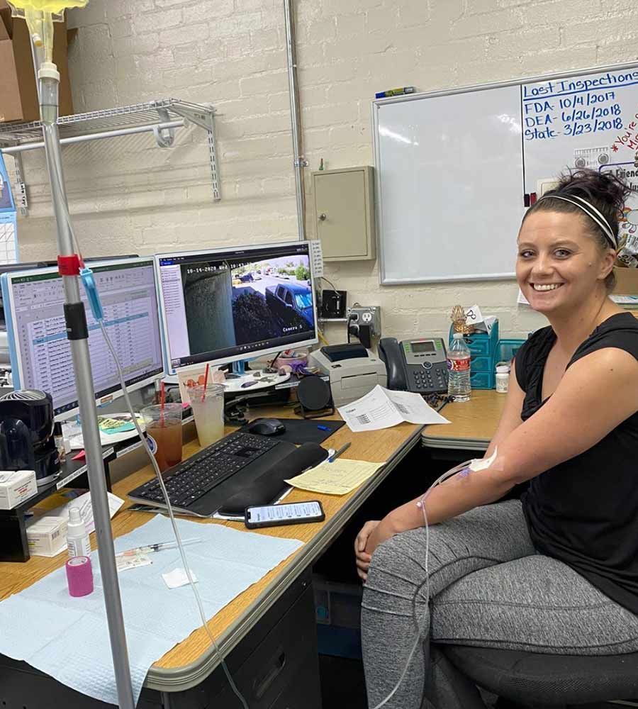 An office worker receiving an IV infusion while staying productive at their desk.