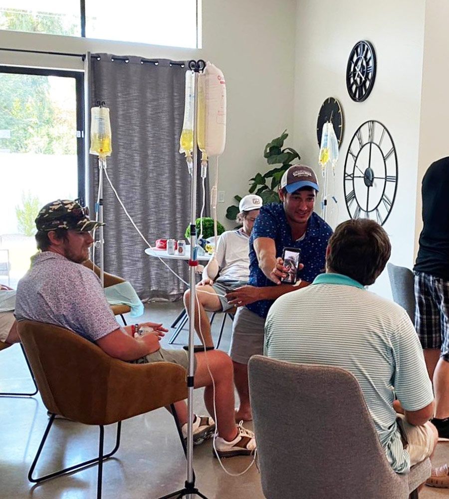 A group of men socialising in a bright living room during a mobile IV hydration event.