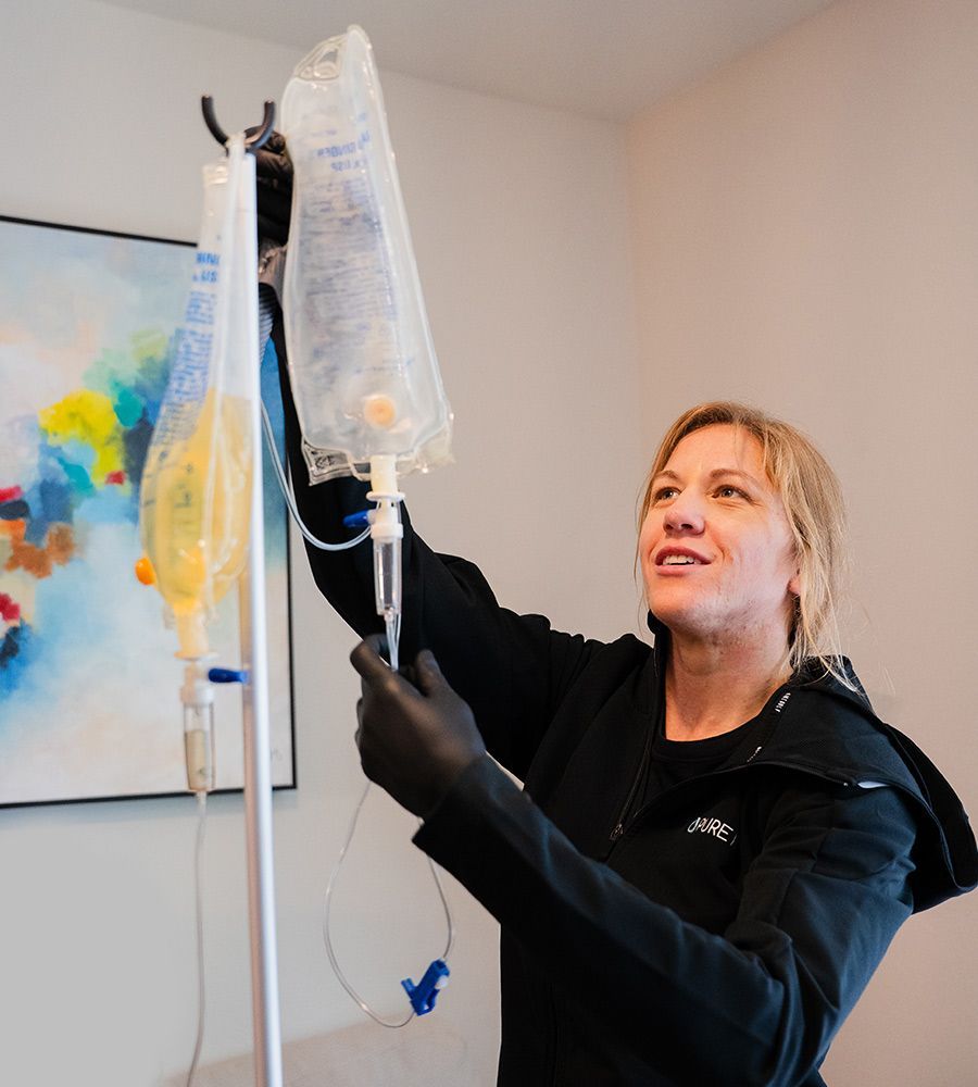 Professional mobile IV nurse preparing customized vitamin infusions, with multiple bags visible, emphasizing personalized care and convenient service delivery in a modern environment.