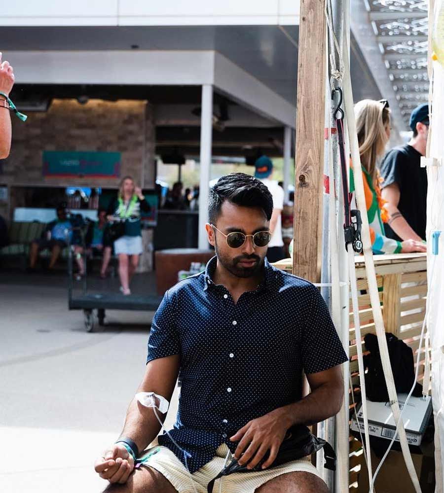 Man in sunglasses and navy polka dot shirt, sitting outside, with IV drip.