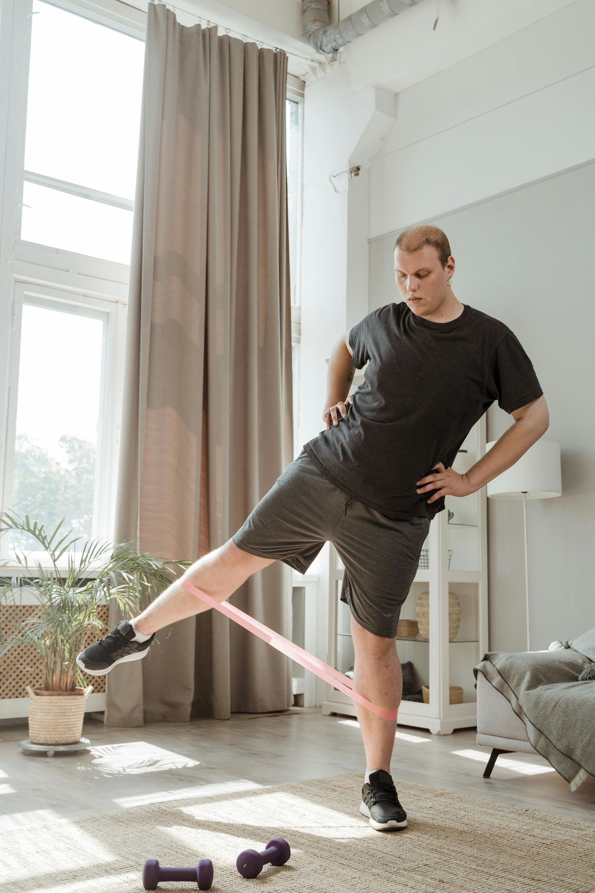 Person in athletic gear doing leg lift with resistance band indoors.