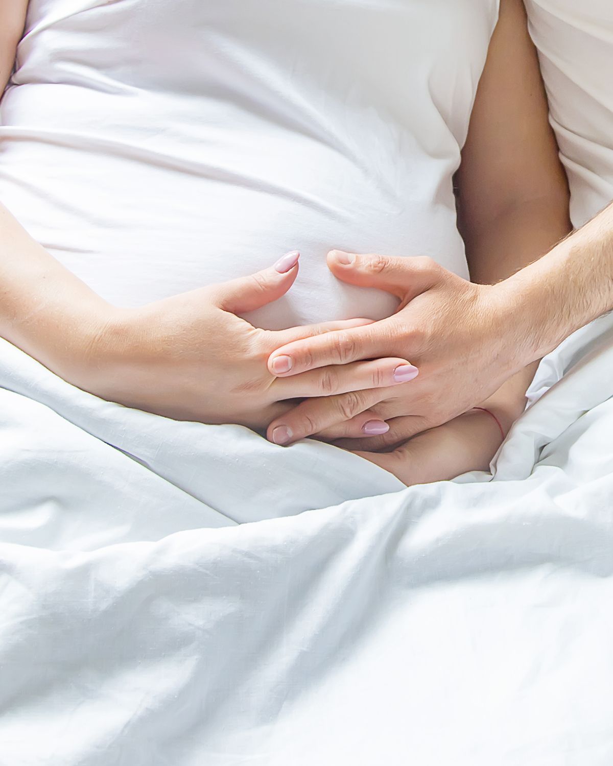 A healthcare professional in scrubs prepares an IV for a patient in a white robe seated in a chair.