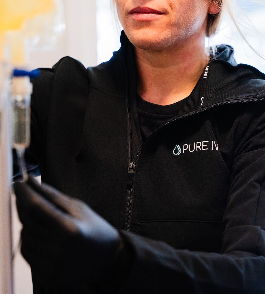 Person in black jacket and gloves holding IV bag. 