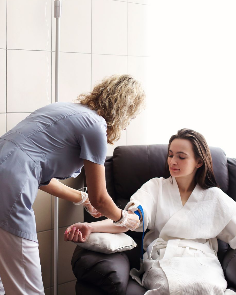 Nurse giving patient an IV treatment in a medical setting.