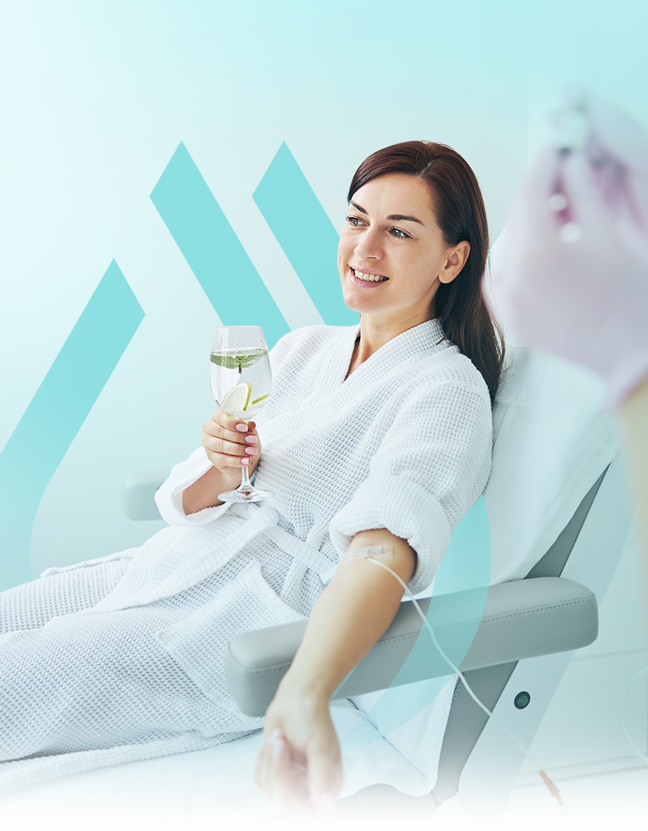 Woman in bathrobe receiving IV drip, holding drink, smiling. White, light blue backdrop.