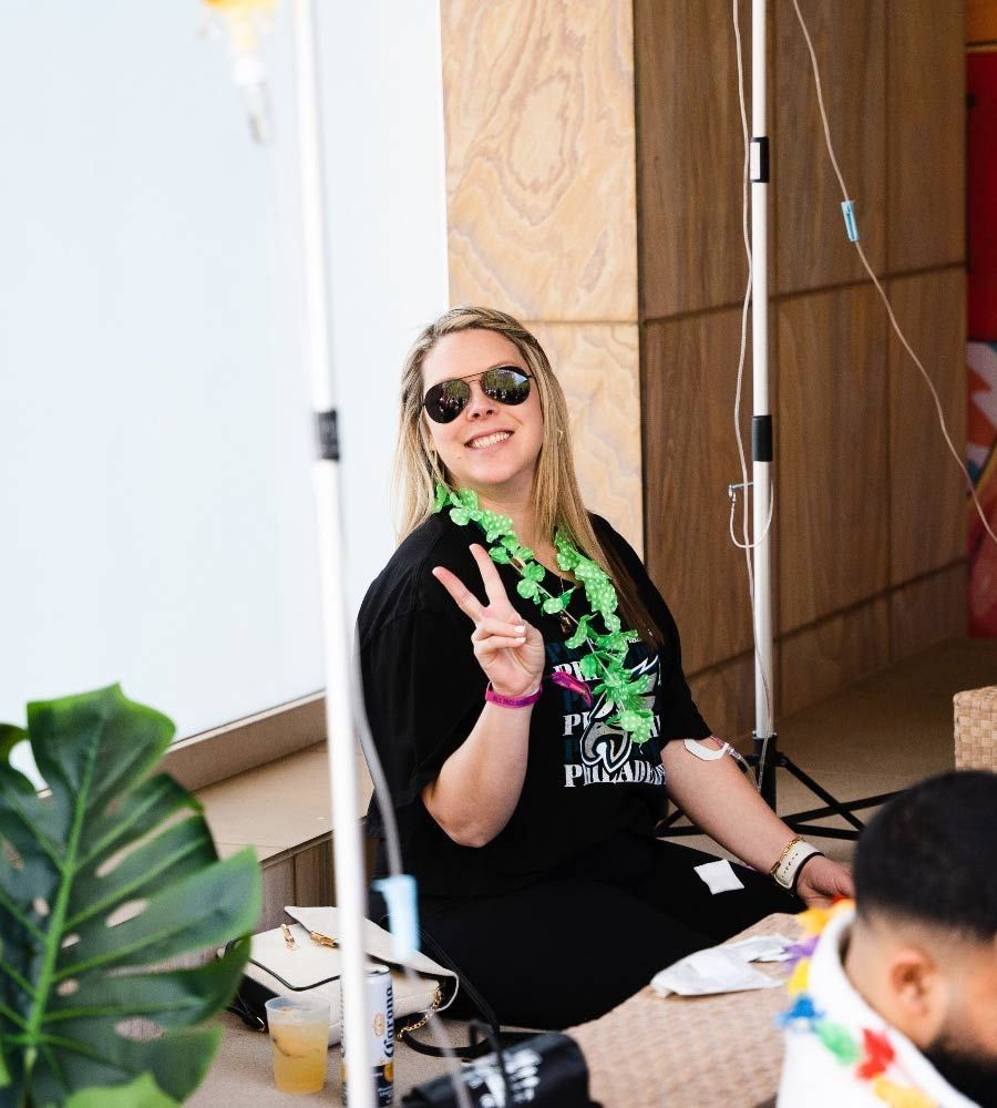 Mobile IV therapy for hangover recovery at a pool party or group event, showing a smiling female client.