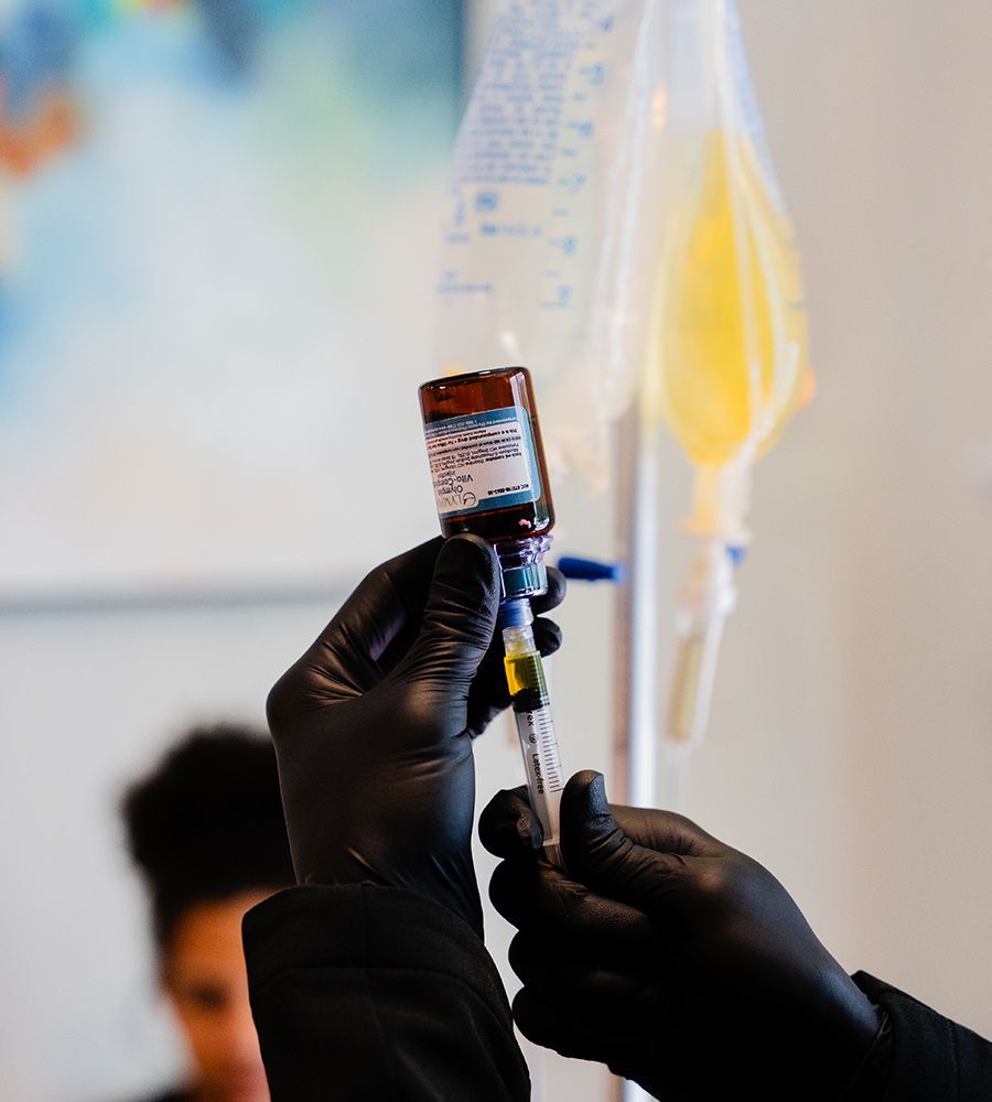 Mobile IV therapy specialist preparing custom nutrient solution by extracting high-quality vitamins, showcasing attention to detail in the preparation process.