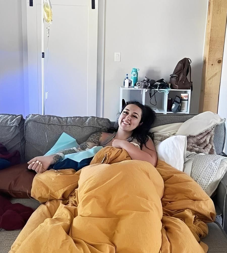 Woman cozy under blanket receiving IV drip at home