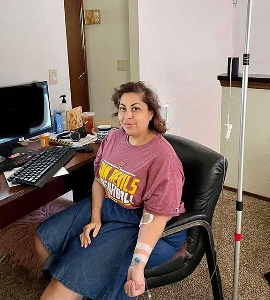 A woman receives mobile IV drip therapy while sitting at her home office desk, emphasizing treatment convenience and minimal workflow interruption.