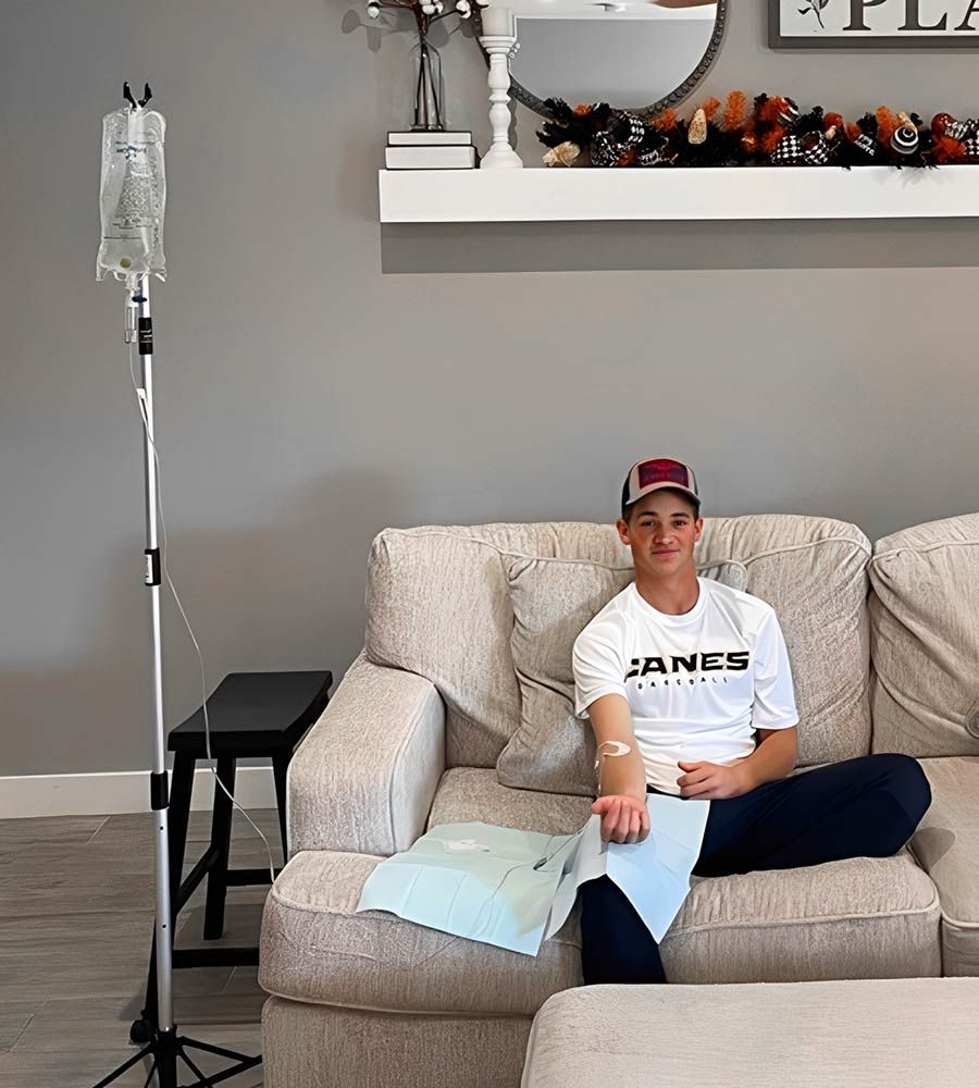 Happy young man receiving a comfortable, in-home IV vitamin therapy infusion on his living room couch.