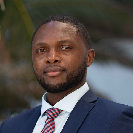 Man in a suit and tie looking at the camera with a neutral expression.