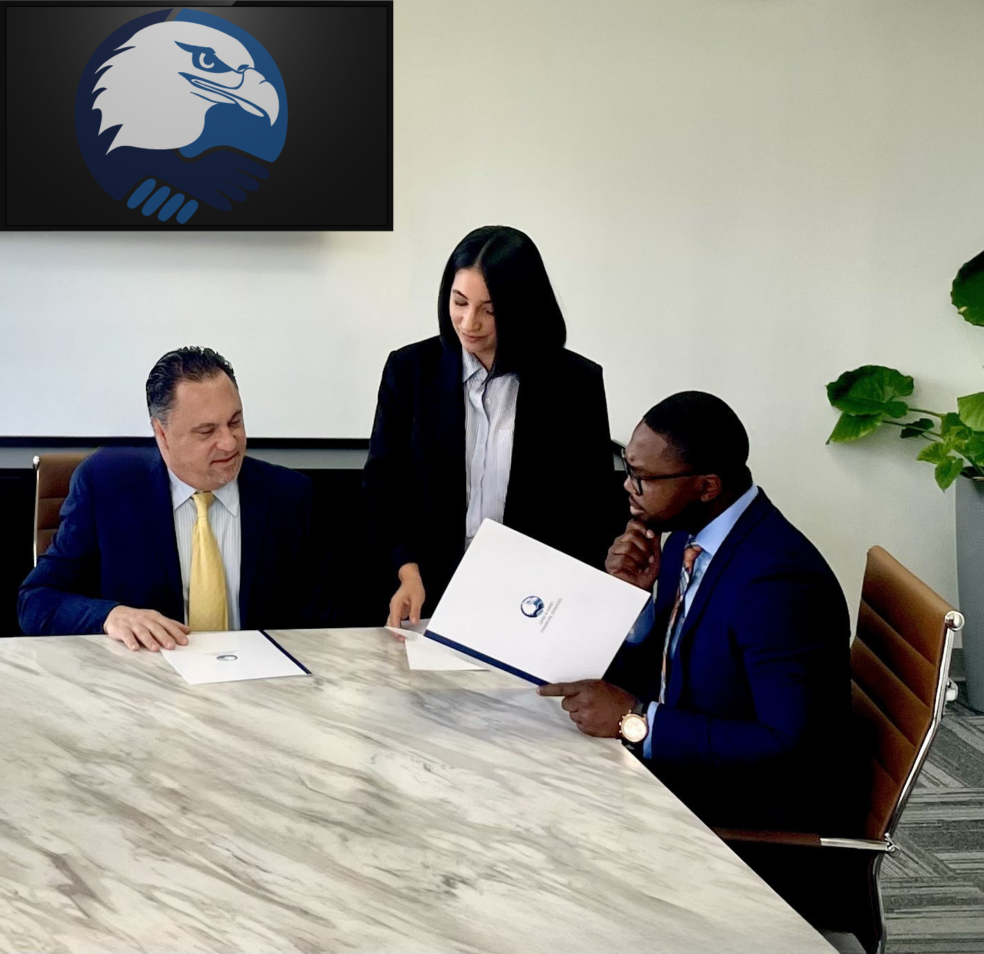 Three professionals in suits review documents around a table, office setting.
