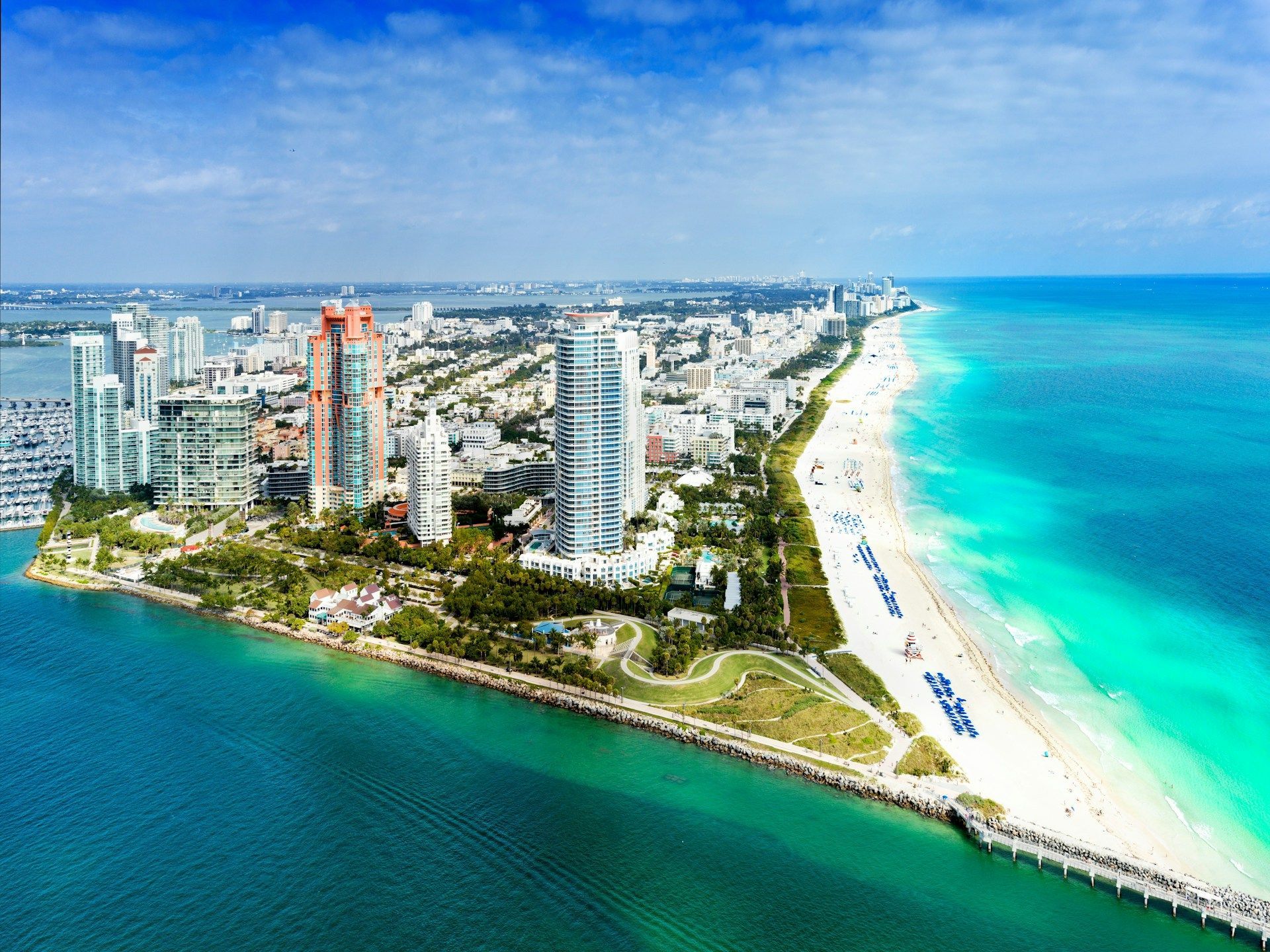 Miami Beach coastline with buildings, beach, and ocean, under a blue sky.