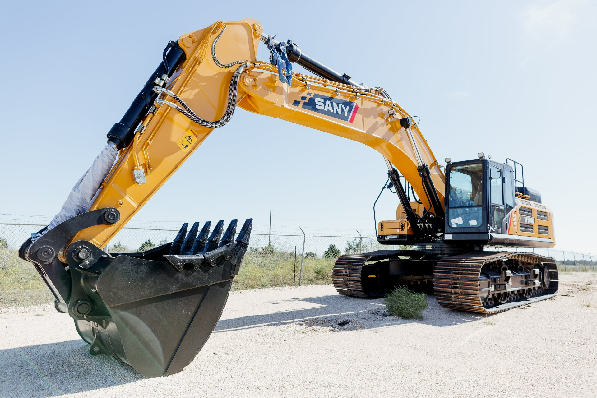 A large yellow excavator is parked on a gravel road.