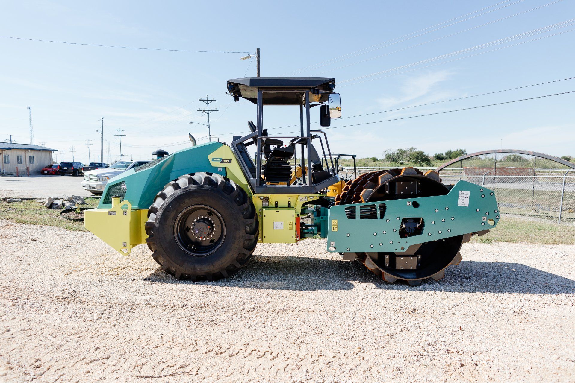 A large green and yellow tractor is parked in a gravel lot.