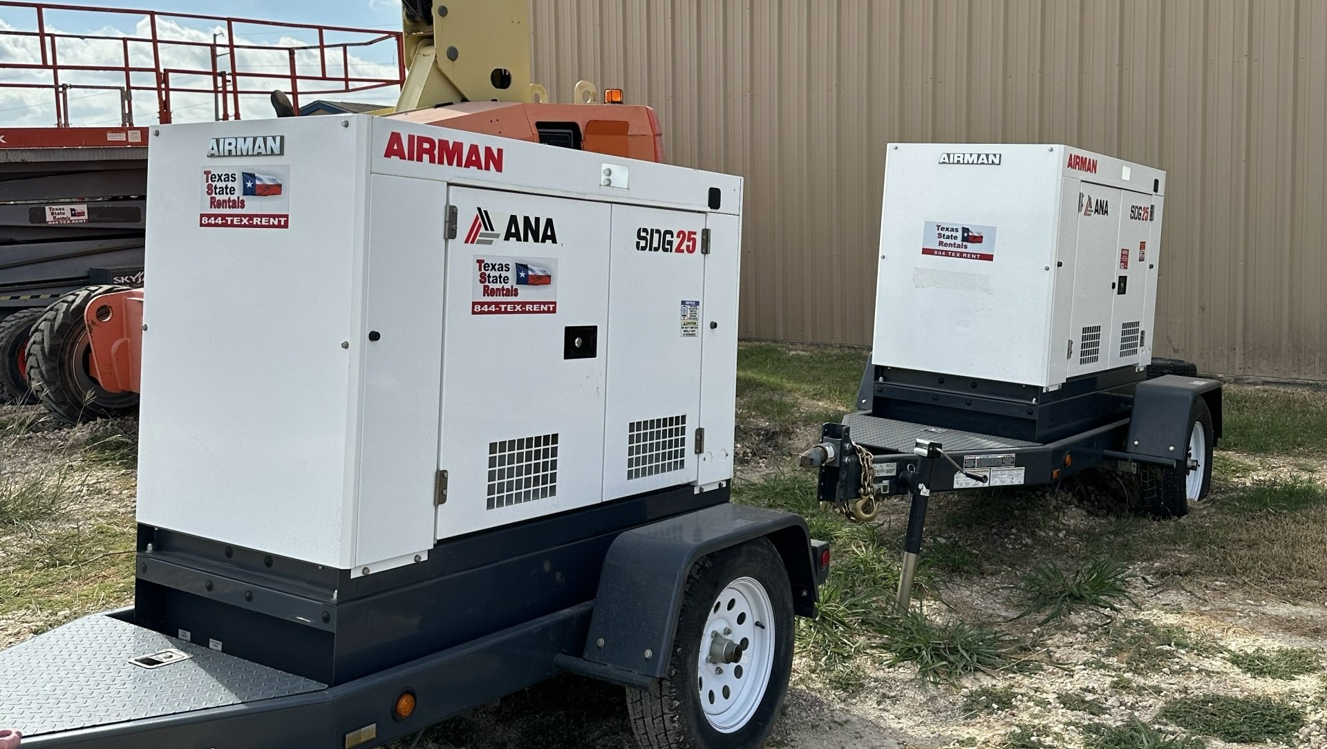 Two generators are sitting on a trailer in a field.