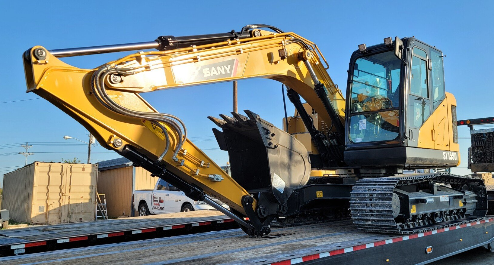 A large yellow excavator is sitting on top of a trailer.