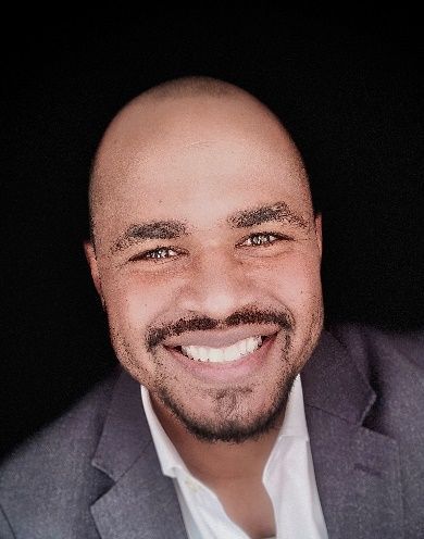 A man in a suit and white shirt is smiling for the camera.