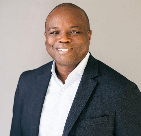 A man in a suit and white shirt is smiling for the camera.