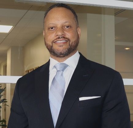 A man in a suit and tie is smiling for the camera