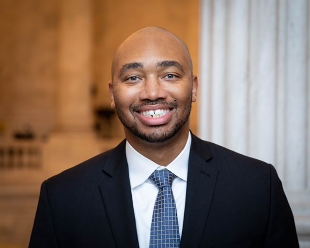 A man in a suit and tie is smiling for the camera.