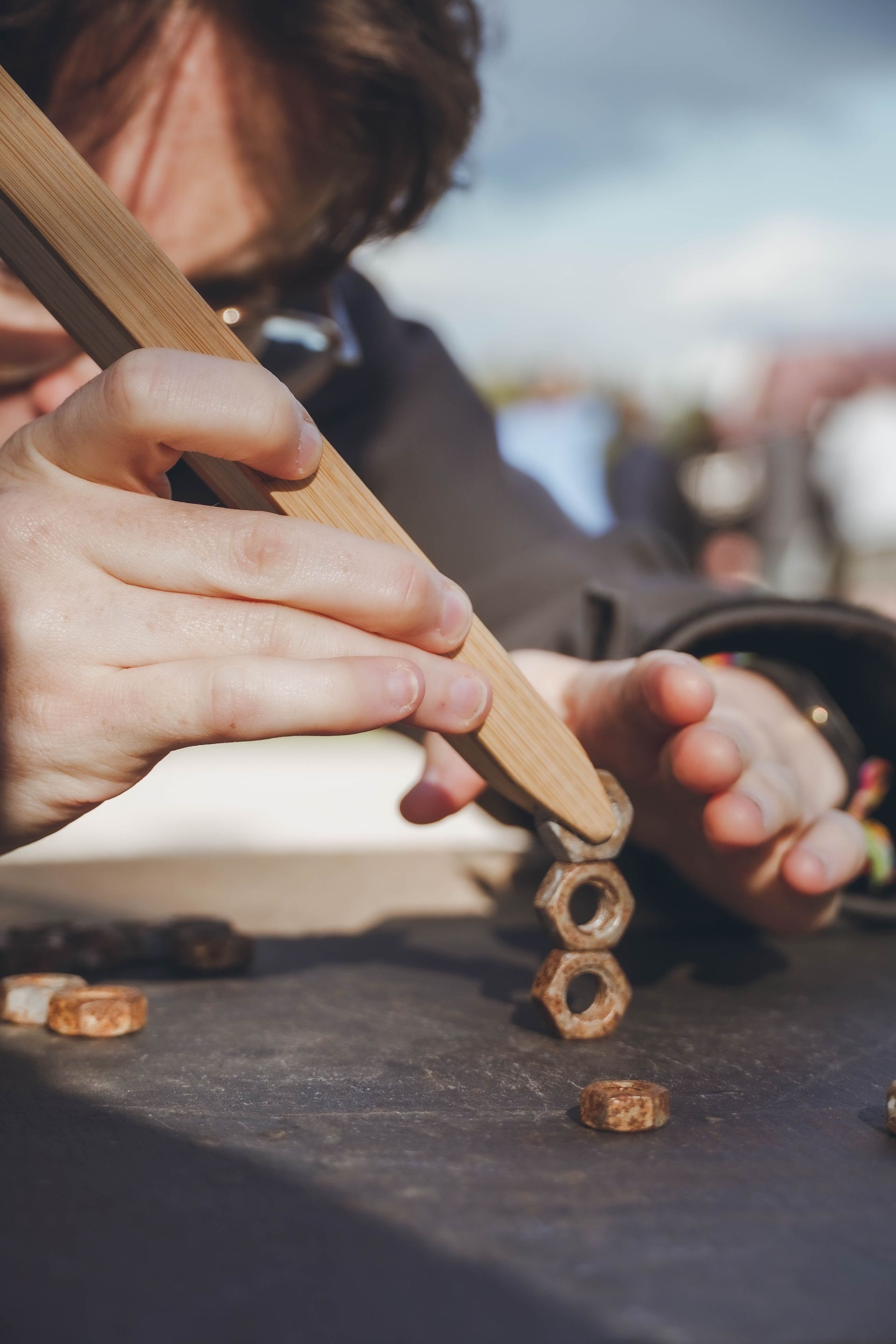 Une personne tient un bâton en bois au-dessus d'un tas de noix.