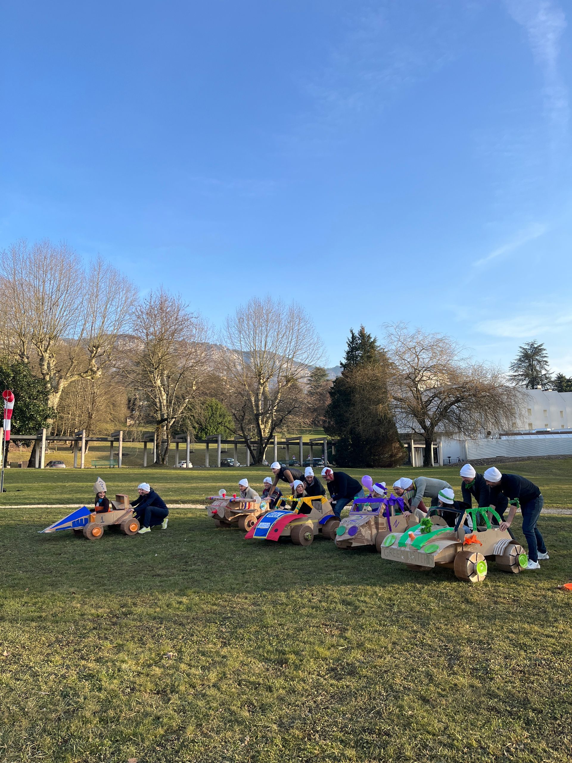Scène de nuit enneigée avec tipi, structure en bois et guirlandes lumineuses ; arbres en arrière-plan.