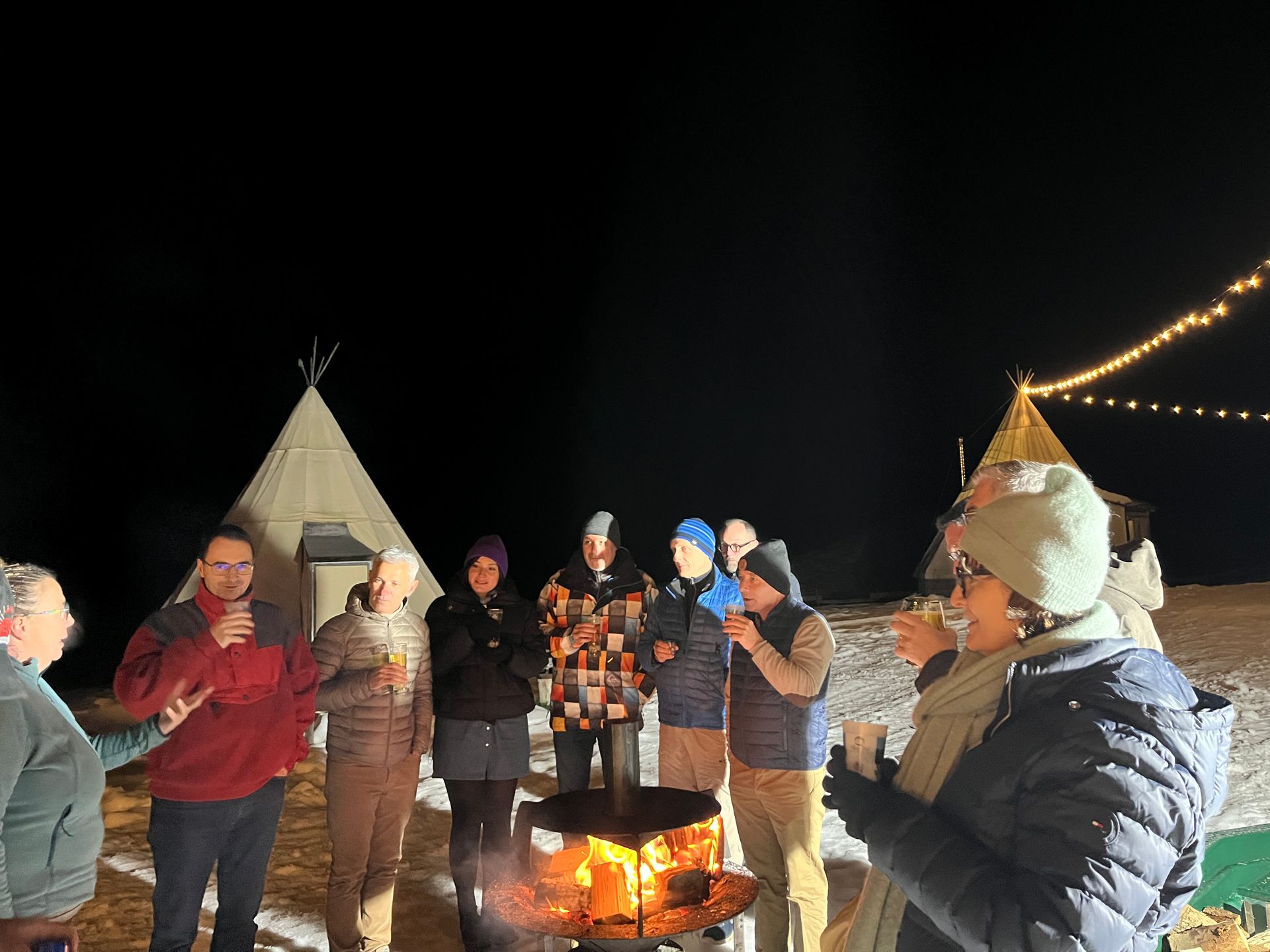 Le soir, des gens se rassemblaient autour d'un foyer près de tipis, tenant des tasses et discutant.