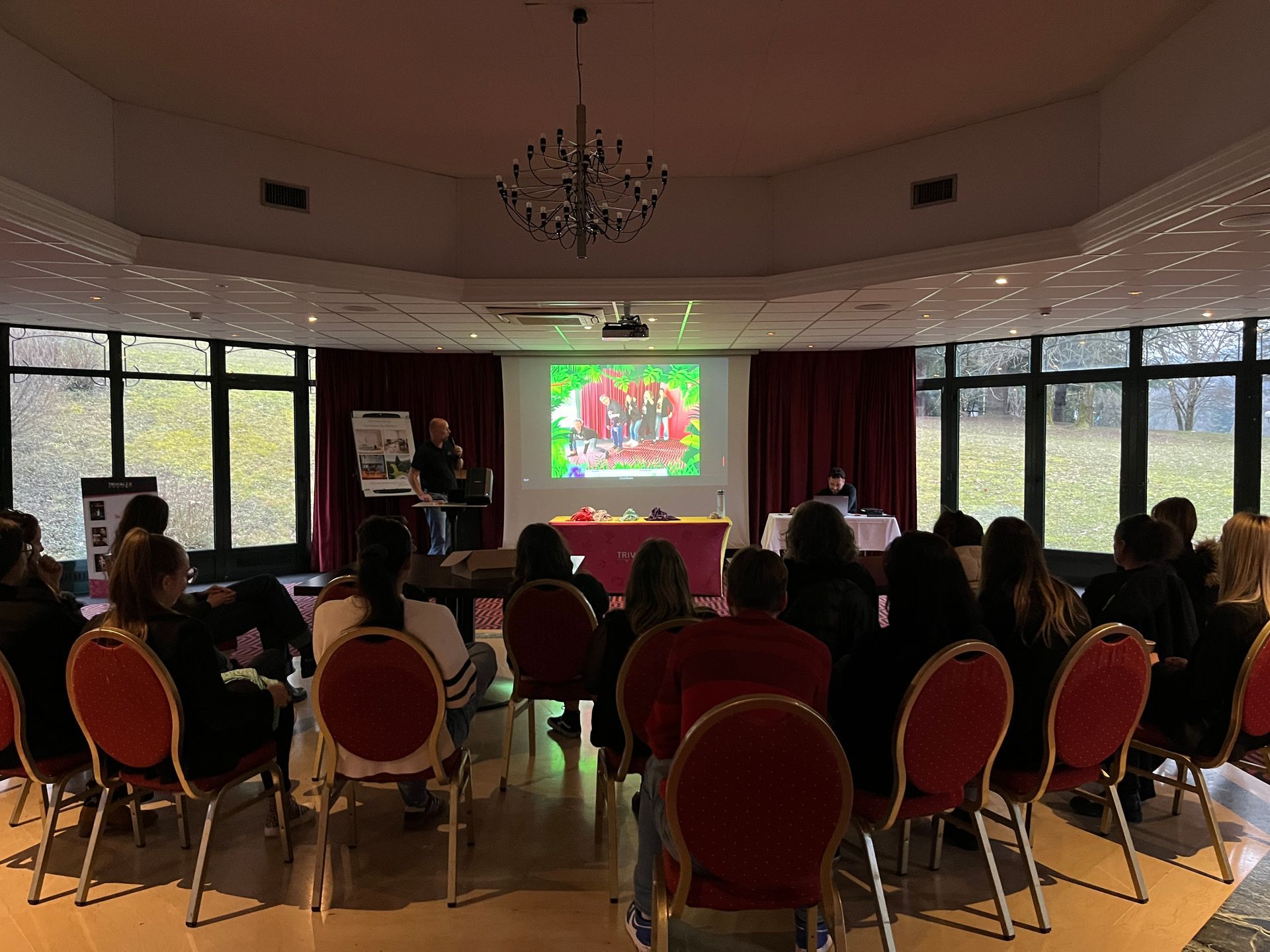 Une présentation dans une salle de conférence avec des participants, un écran de projection et un orateur.
