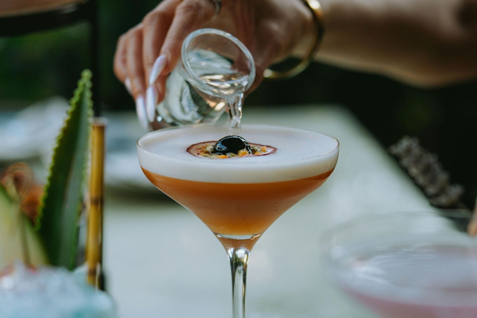 Une personne verse une boisson dans un verre à martini.