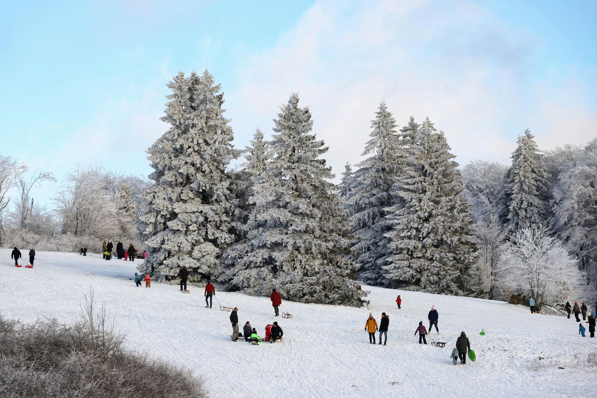 Un groupe de personnes dévale une colline enneigée en luge.