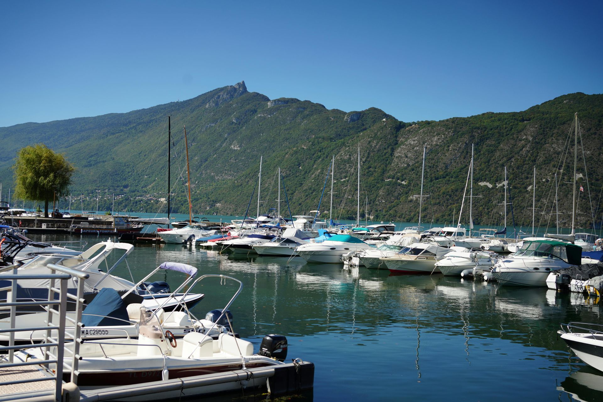 De nombreux bateaux sont amarrés dans une marina avec des montagnes en arrière-plan