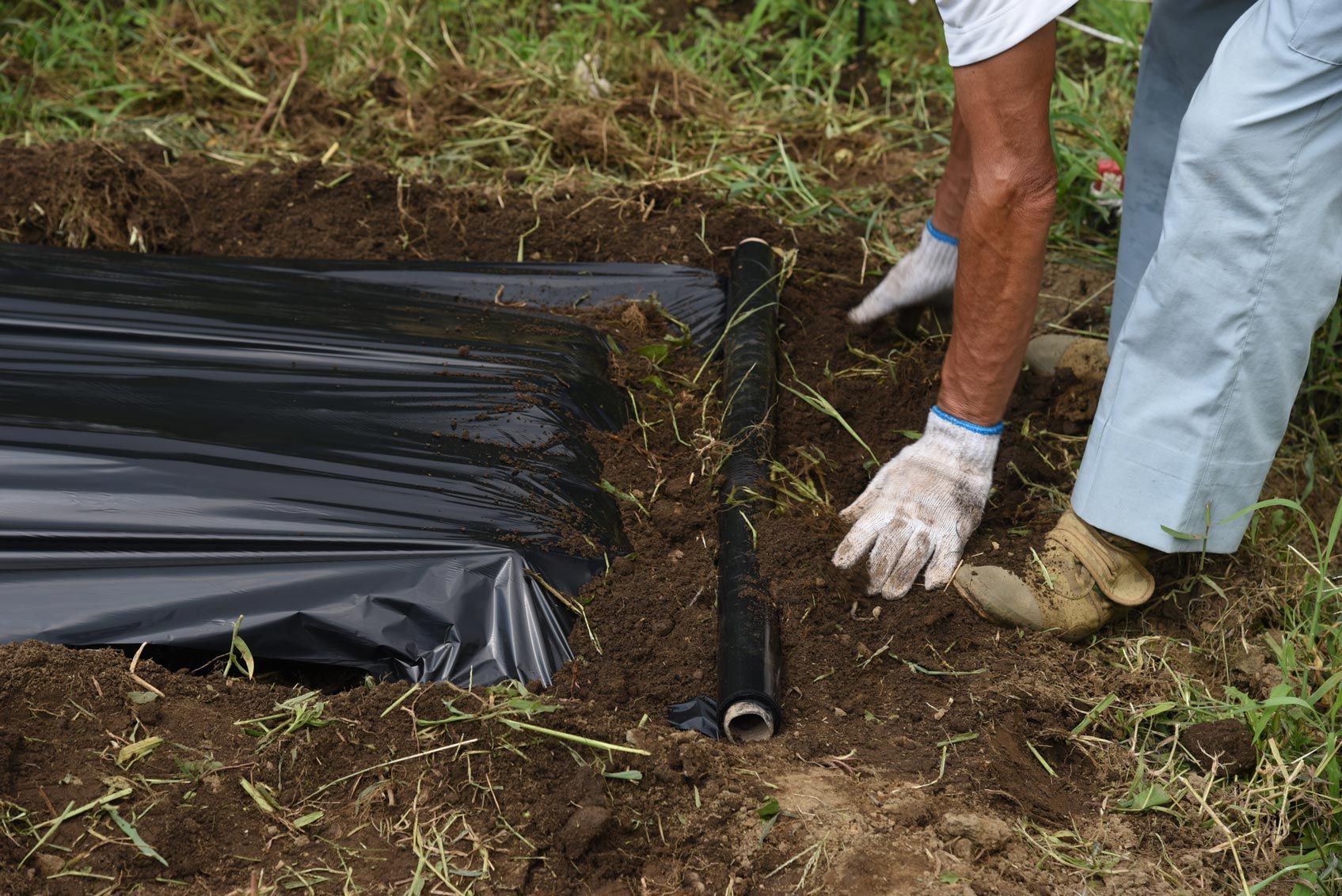 A person is laying a pipe in the dirt.