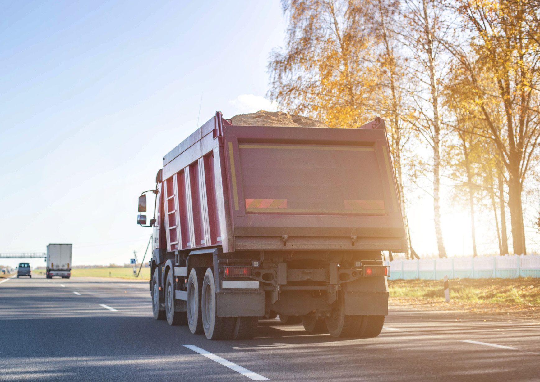 A red dump truck is driving down a highway.