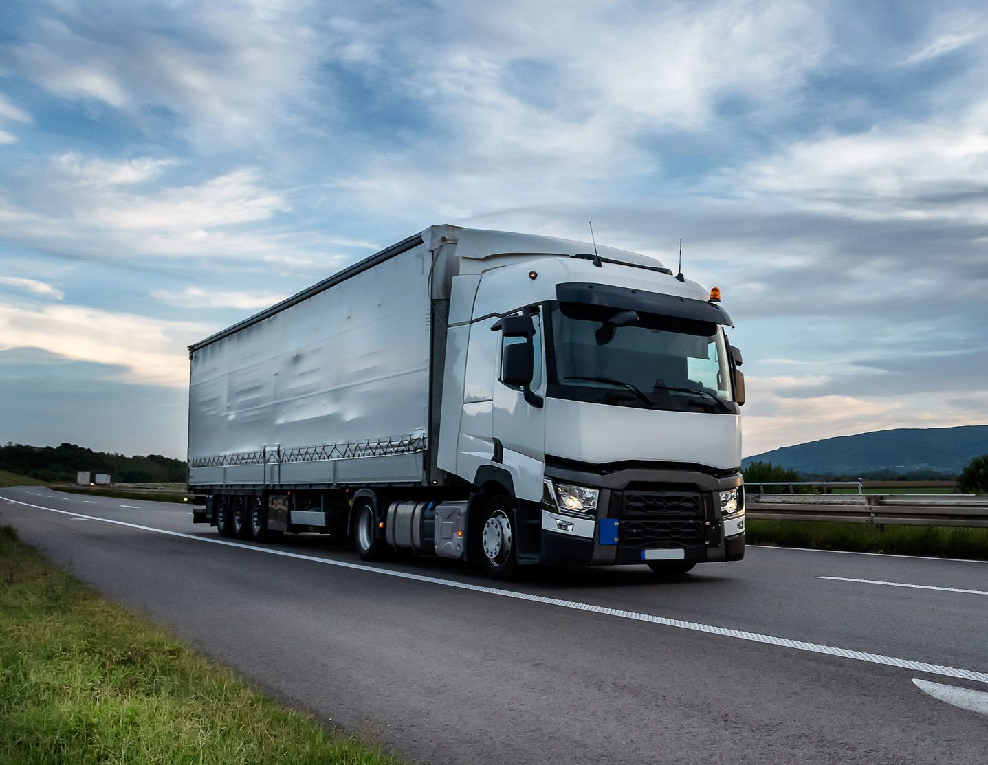 A white semi truck is driving down a highway.
