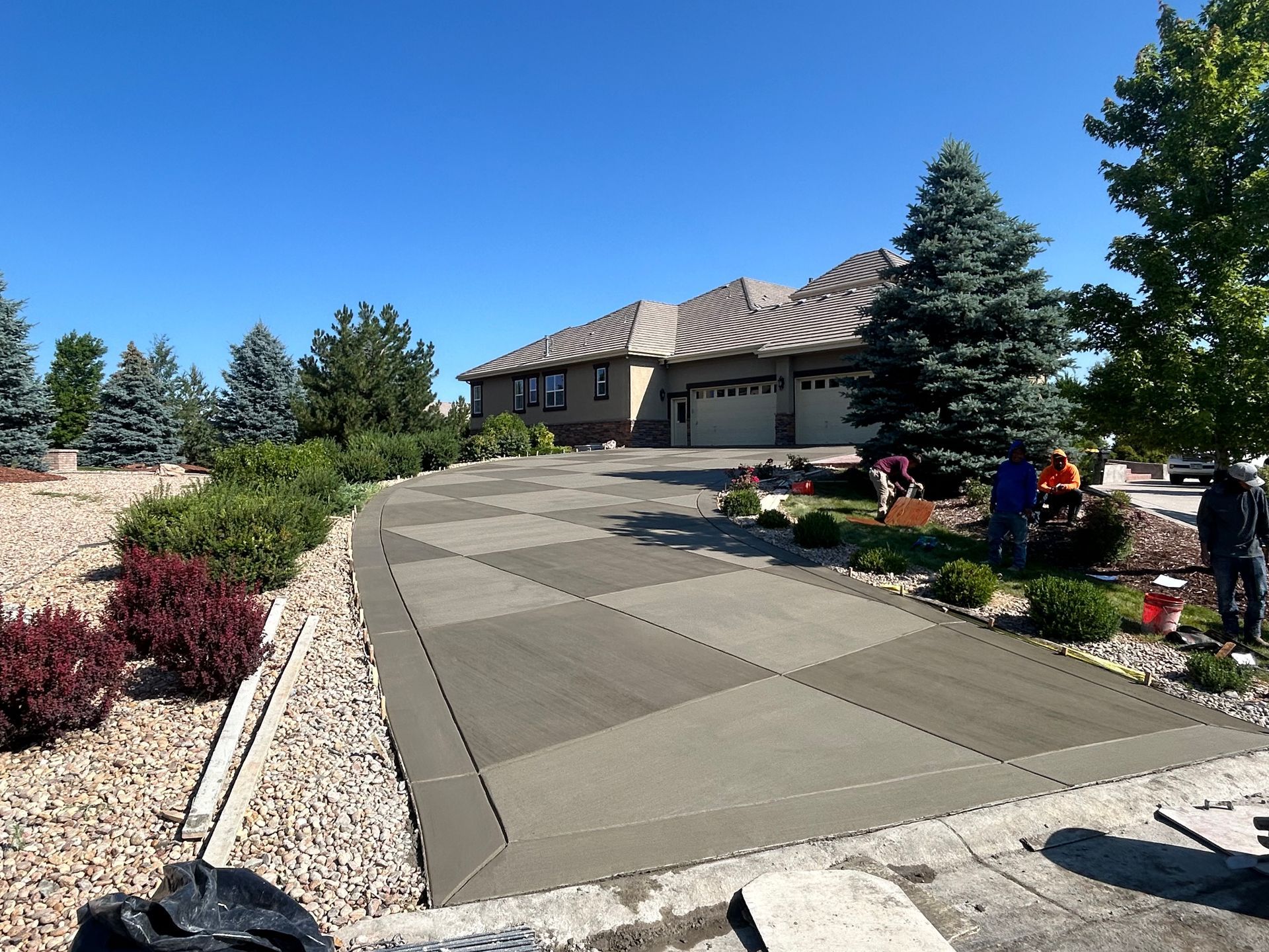 Landscaped driveway leading to a modern house with stone borders and blue sky