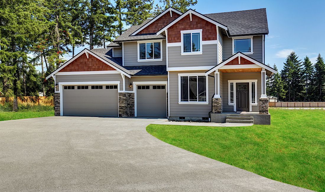 Concrete driveway leading up to a modern two-story house.