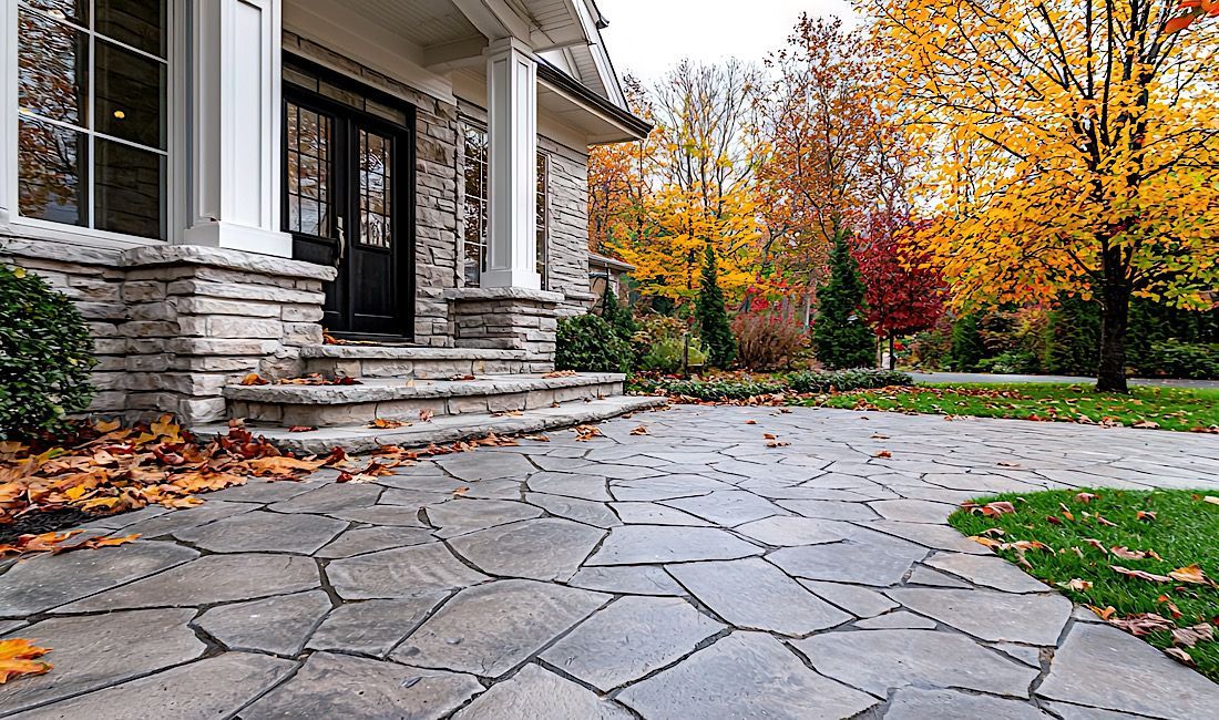 Gorgeous stamped concrete walkway leading up to house, fall leaves and trees surrounding house.